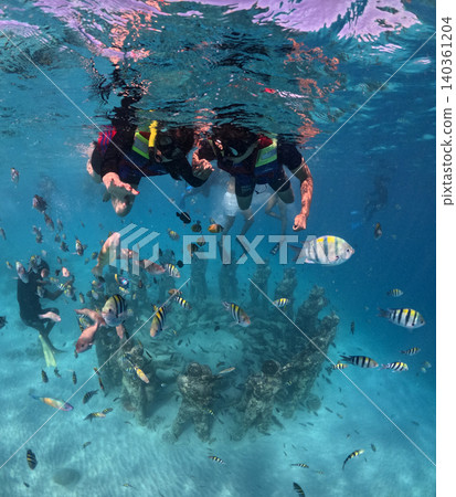 Snorkel with tropical fish above the underwater sculpture garden in the crystal clear ocean. 140361204