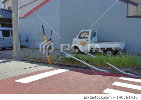 Road sign knocked down in a traffic accident and impact damage to a house. 140361436
