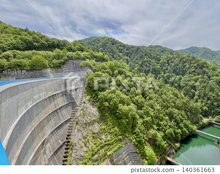 Yagisawa Dam in early summer, with rainbow-colored clouds (iridescent clouds) in the sky, Minakami Town, Gunma Prefecture. Yagisawa Dam in early summer, with rainbow-colored clouds (iridescent clouds) in the sky, Minakami Town, Gunma Prefecture. 140361663