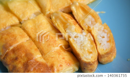 roll omelette stuffed with chesse and rice on blue plate, delicious food in the morning roll omelette stuffed with chesse and rice on blue plate, delicious food in the morning 140361735