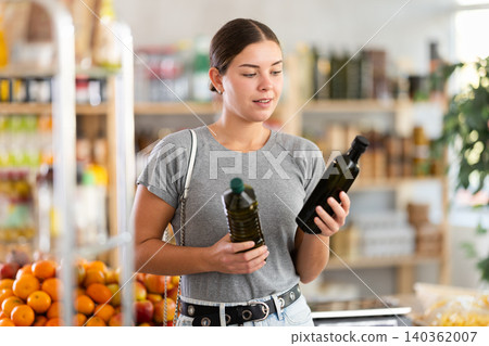European youth girl choose and buy olive oil in store European youth girl choose and buy olive oil in store 140362007