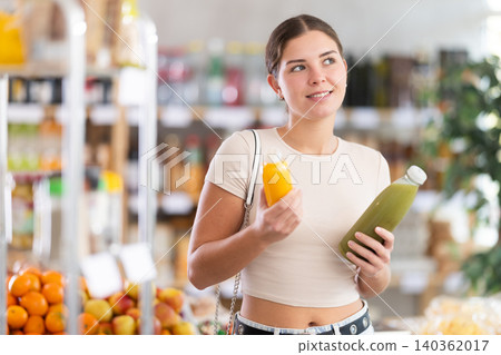 European smiling girl hold bottle, choose and buy smoothie in store 140362017