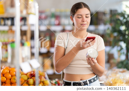 Young woman scanning qr code of canned food 140362111