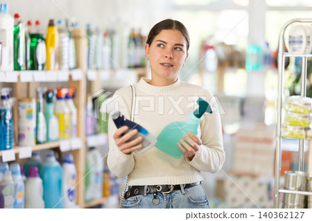 Woman choosing a cleaning spray Woman choosing a cleaning spray 140362127