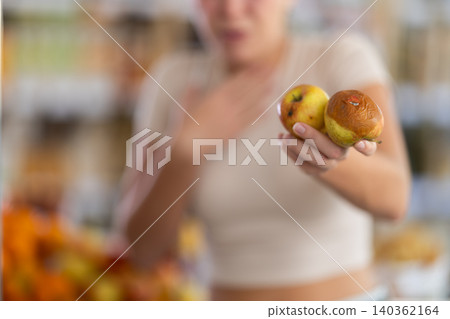 Woman holds rotten apples in grocery store 140362164