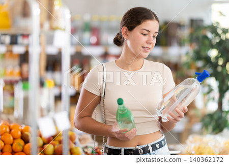 Girl hold bottles, choose and buy soda in store 140362172