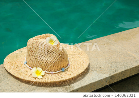 A straw hat rests on the edge of a pool in Bali A straw hat rests on the edge of a pool in Bali 140362321