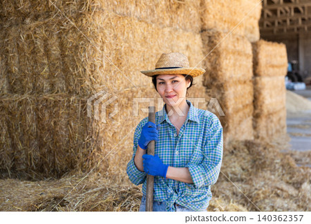 Cow farm owner posing in the barn against backdrop of hay bales 140362357