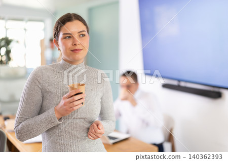 Young woman drinking coffee in office Young woman drinking coffee in office 140362393