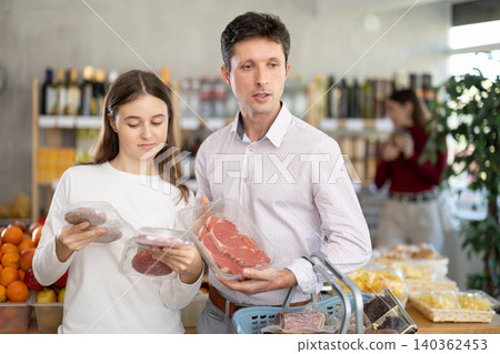 Man and his teenage daughter choosing hamburger or beef entrecote in grocery 140362453