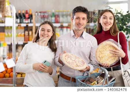 man and woman with girl choosing pizza in grocery man and woman with girl choosing pizza in grocery 140362476