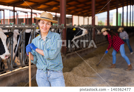 Young adult woman farmer working in cowshed Young adult woman farmer working in cowshed 140362477