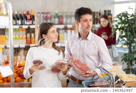 Man and his teenage daughter choosing hamburger or beef entrecote in grocery 140362497