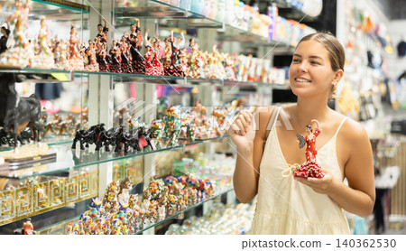 Female buyer holds in hands tests figurine she-dancer flamenco in memorable gifts shop Female buyer holds in hands tests figurine she-dancer flamenco in memorable gifts shop 140362530