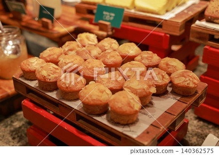 Freshly baked mini almond muffins topped with sliced nuts served on a wooden tray at a hotel breakfast buffet. Delicious sweet dessert pastry for morning brunch catering and bakery display. Freshly baked mini almond muffins topped with sliced nuts served on a wooden tray at a hotel breakfast buffet. Delicious sweet dessert pastry for morning brunch catering and bakery display. 140362575