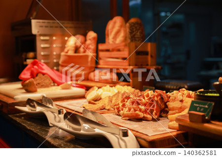 Freshly baked golden waffles, french toast, and rustic bread loaves displayed at a luxury hotel breakfast buffet station. Morning bakery catering setup with serving tongs under warm ambient lighting. Freshly baked golden waffles, french toast, and rustic bread loaves displayed at a luxury hotel breakfast buffet station. Morning bakery catering setup with serving tongs under warm ambient lighting. 140362581