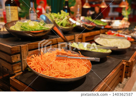 Fresh organic salad bar buffet station in luxury hotel restaurant. Close up of shredded carrots, cucumber and lettuce in metal bowls for healthy vegetarian dining catering and morning brunch. Fresh organic salad bar buffet station in luxury hotel restaurant. Close up of shredded carrots, cucumber and lettuce in metal bowls for healthy vegetarian dining catering and morning brunch. 140362587