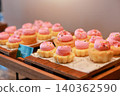 Freshly baked mini cupcakes with pink buttercream frosting and colorful sprinkles arranged on wooden trays at a luxury hotel dessert buffet. Sweet bakery pastry for morning brunch catering display. 140362590