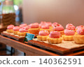 Freshly baked mini cupcakes with pink buttercream frosting and colorful sprinkles arranged on wooden trays at a luxury hotel dessert buffet. Sweet bakery pastry for morning brunch catering display. 140362591