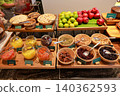 Healthy breakfast buffet display at a luxury hotel restaurant featuring fresh apples, oranges, various dried fruits, nuts, seeds, and cereals in wooden bowls and glass jars for morning catering. 140362593