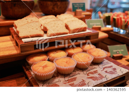 Freshly baked sliced gluten free bread and plain vanilla muffins arranged on rustic wooden trays at a luxury hotel breakfast buffet. Sweet pastry and bakery catering display for morning meal. 140362595