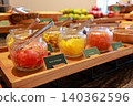 Close up of colorful dried fruits like cantaloupe and mango in glass jars with serving tongs on a wooden tray at a luxury hotel breakfast buffet. Healthy sweet snack for morning catering display. 140362596