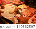 Unrecognizable person using metal tongs to pick up sweet french toast and pancakes onto a white plate at a luxury hotel breakfast buffet. Morning bakery catering service with delicious food. 140362597