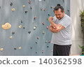 Overweight Asian man suffering from elbow joint pain with glowing bone anatomy graphic overlay after rock climbing exercise. Sports injury, arthritis and muscle inflammation medical healthcare concept 140362598