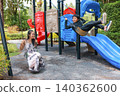 Happy Asian woman and boy playing on swings at colorful outdoor park playground, smiling and laughing together. Family leisure time and joyful childhood moment in daylight. 140362600
