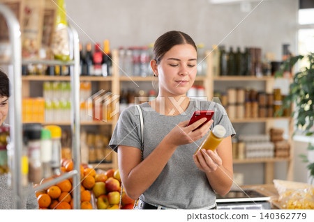 In shop youth girl scan QR code and take reading smoothie package bottle using phone camera In shop youth girl scan QR code and take reading smoothie package bottle using phone camera 140362779