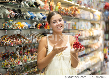 Female buyer holds in hands tests figurine she-dancer flamenco in memorable gifts shop Female buyer holds in hands tests figurine she-dancer flamenco in memorable gifts shop 140362802