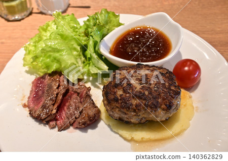 A luxurious meat dish combo plate featuring a thick hamburger steak and a rare steak. A luxurious meat dish combo plate featuring a thick hamburger steak and a rare steak. 140362829