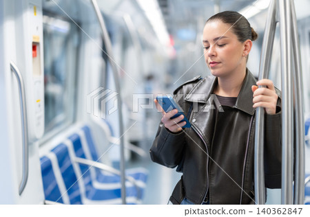 Girl stands in subway car and writes message on her smartphone screen 140362847