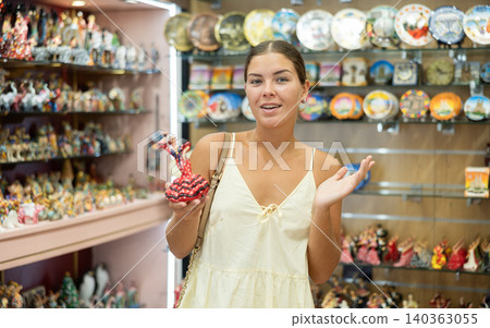 Happy young woman choosing statue of Spanish dancer among various souvenirs in gift shop in Barcelona Happy young woman choosing statue of Spanish dancer among various souvenirs in gift shop in Barcelona 140363055