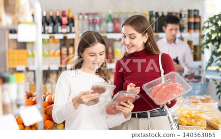 Woman with daughter chooses hamburger or entrecote Woman with daughter chooses hamburger or entrecote 140363065