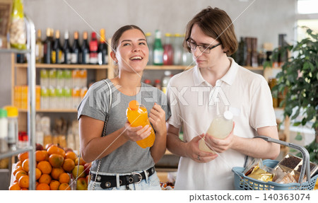 Youth girl and guy friends hold packages bottles and choose consider drink in store Youth girl and guy friends hold packages bottles and choose consider drink in store 140363074