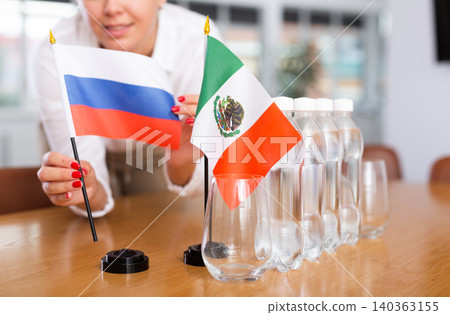 Unrecognizable girl sets midget flags of Mexico and Russia before international negotiations Unrecognizable girl sets midget flags of Mexico and Russia before international negotiations 140363155