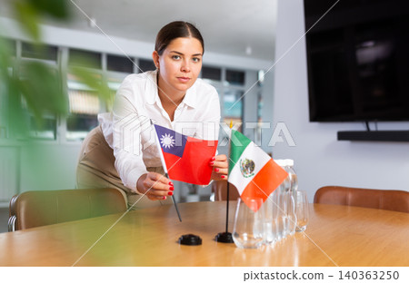 Woman secretary prepares an office for negotiations - she places flags of Taiwan and Mexico table Woman secretary prepares an office for negotiations - she places flags of Taiwan and Mexico table 140363250