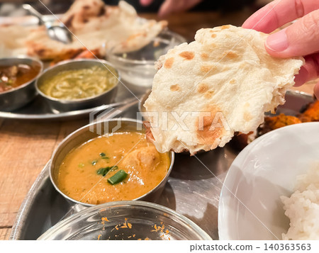 Chicken curry eaten at an Indian curry restaurant. A picture of someone eating the curry with naan bread. Chicken curry eaten at an Indian curry restaurant. A picture of someone eating the curry with naan bread. 140363563