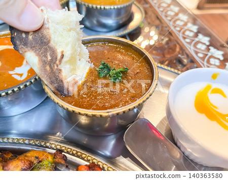在印度咖哩餐廳享用羊肉咖哩。圖片顯示咖哩佐以烤餅食用。 在印度咖哩餐廳享用羊肉咖哩。圖片顯示咖哩佐以烤餅食用。 140363580