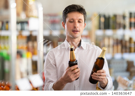 Adult man choosing beer in grocery store Adult man choosing beer in grocery store 140363647