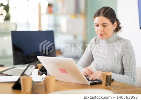 Working in modern office - businesswoman working on laptop 140363958