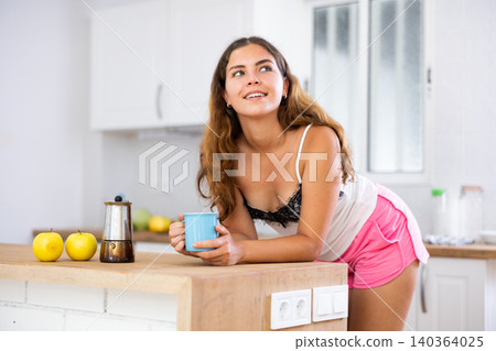 Young woman drinking morning coffee in home kitchen Young woman drinking morning coffee in home kitchen 140364025