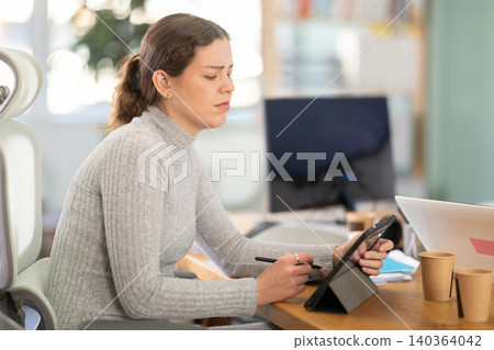 Sad young woman working on computer in office Sad young woman working on computer in office 140364042