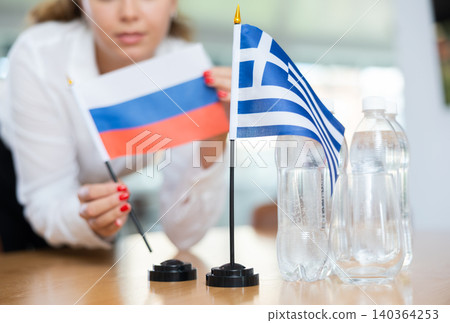 Unrecognizable girl sets midget flags of Greece and Russia before international negotiations Unrecognizable girl sets midget flags of Greece and Russia before international negotiations 140364253