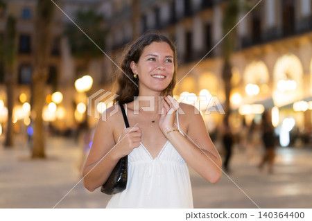 young woman walks along an evening street in Barcelona young woman walks along an evening street in Barcelona 140364400