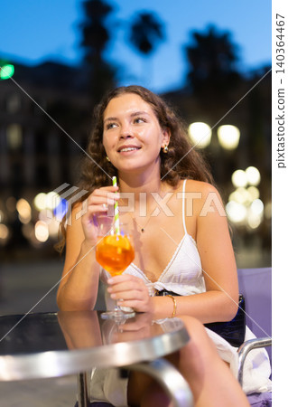 On summer outside of cafe, girl is relaxing at table, drinking chilled coctail. 140364467