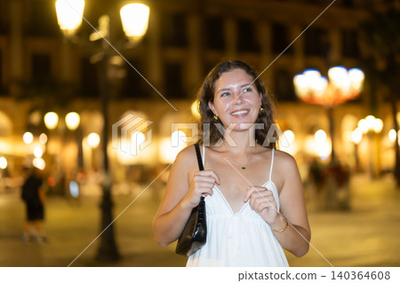 young woman walks along an evening street in Barcelona 140364608
