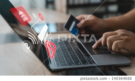 Person holding a credit card while using a laptop with security alert interface, illustrating online payment fraud detection, transaction monitoring, cybersecurity protection and digital banking risk 140364688