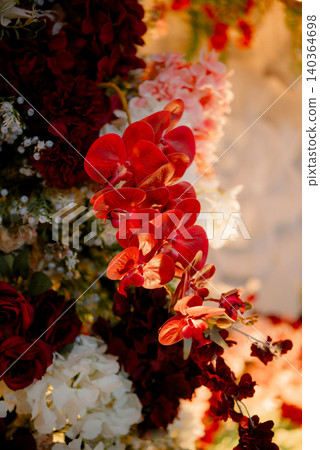 A stunning close-up view of a bright red orchid beautifully integrated into an elegant floral arrangement. 140364698